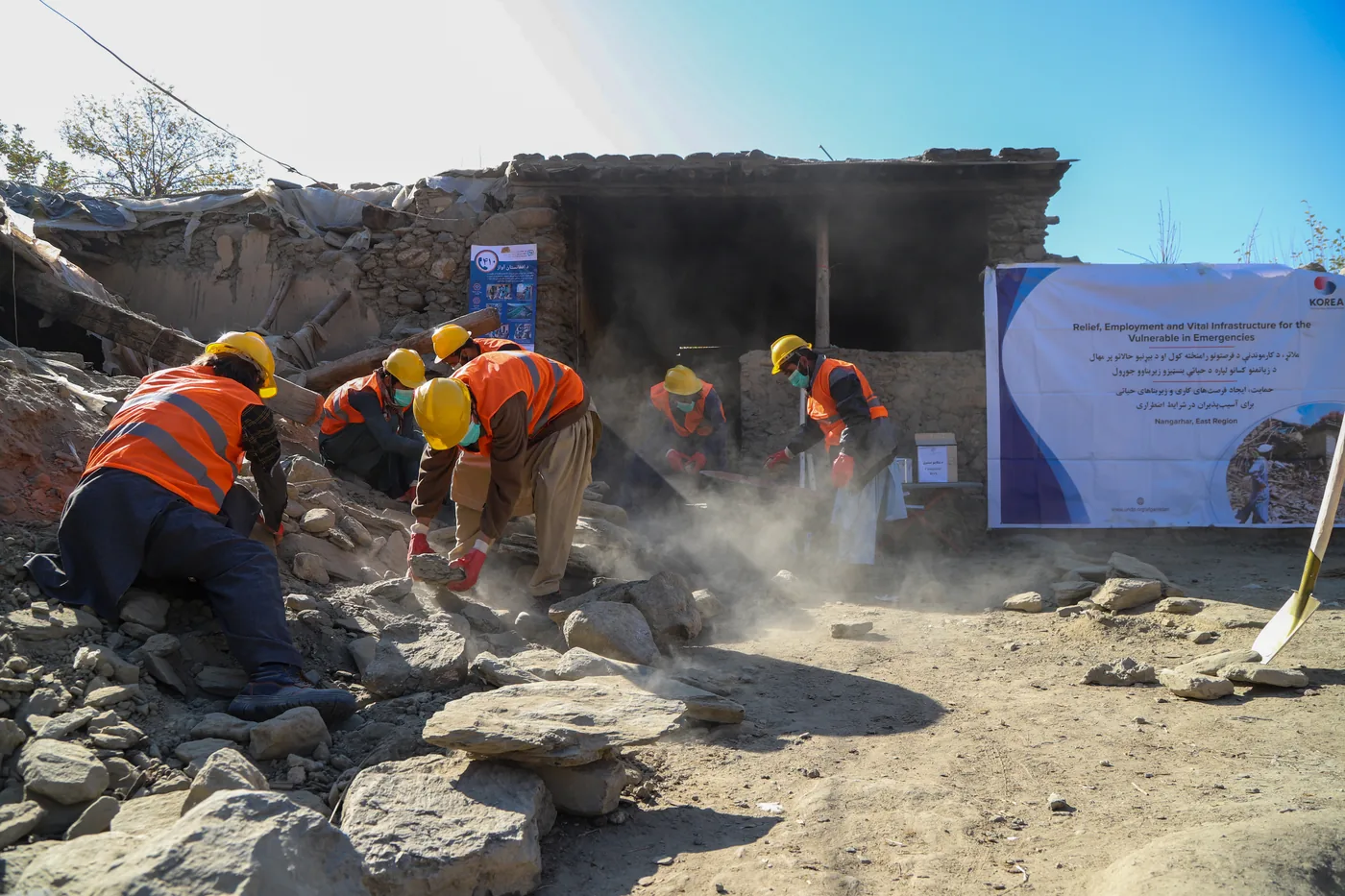 Workers in safety helmets clear rubble from earthquake-damaged buildings